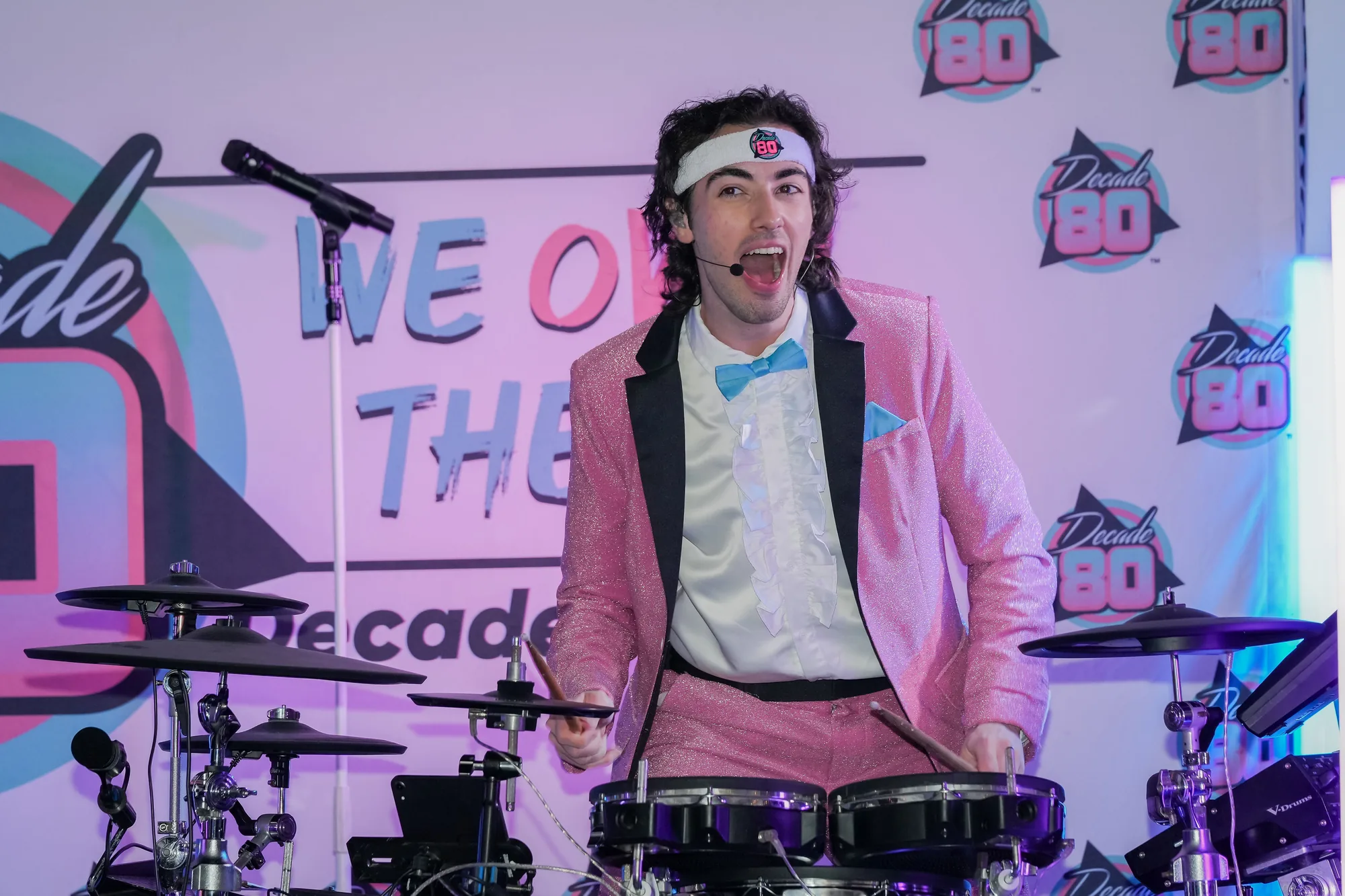 Decade80 drummer performing in a pink tuxedo