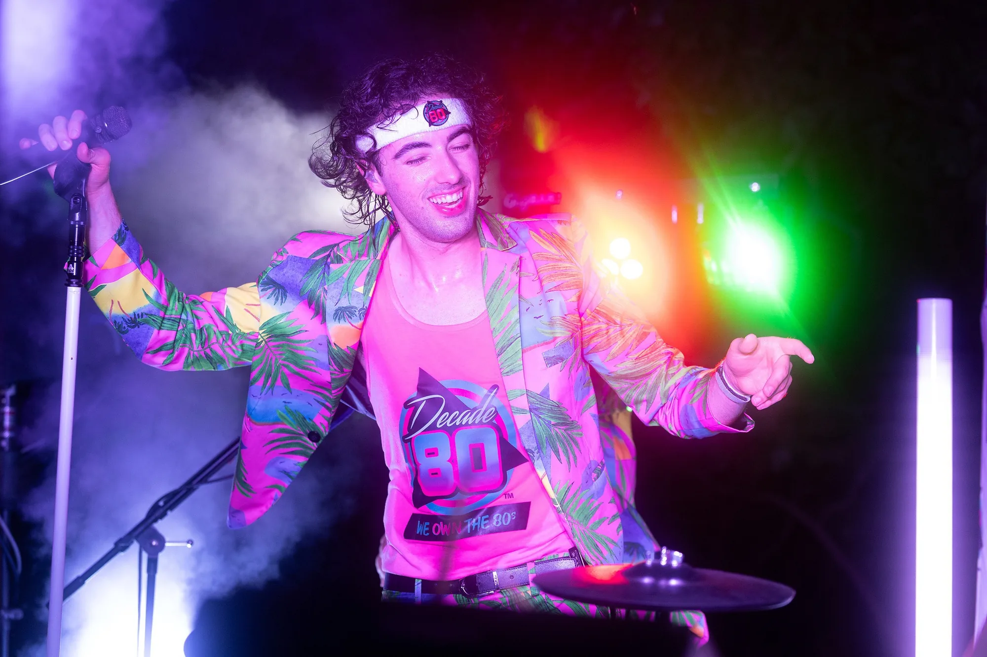 Decade80 singer in a tropical jacket under pink stage lights